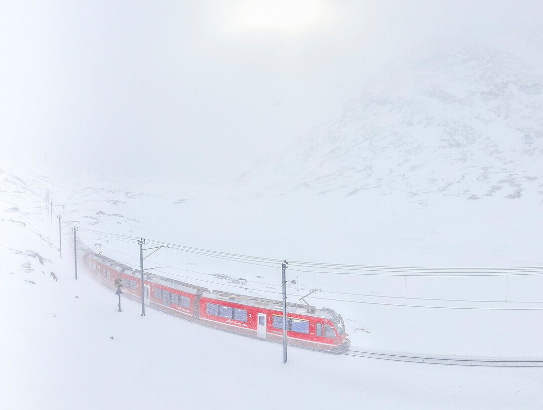 Bernina Express Zug am Bernina Pass während eines Schneesturms, Kanton Graubünden, Engadin, Schweiz