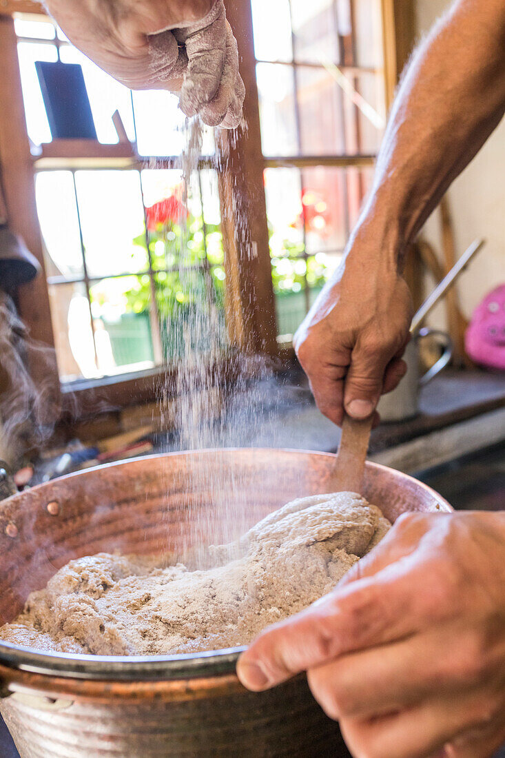 Chef mischen die Zutaten für typische Polenta, San Romerio Alp, Brusio, Kanton Graubünden, Poschiavo Tal, Schweiz