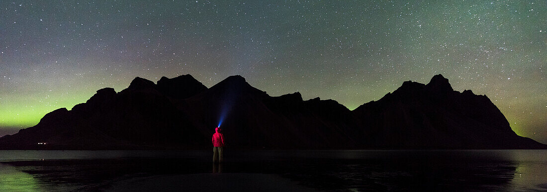 Stokksnes, Hofn, Ost-Island, Island, Ein Mann steht am Strand bei Nacht Blick auf die Nordlichter und Vestrahorn Berg