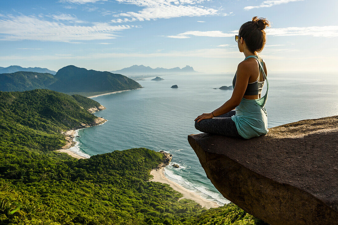 Woman sitting on the edge of the mountain in Pedra do TelÃ©grafo, Barra de Guaratiba, west side of Rio de Janeiro, Brazil