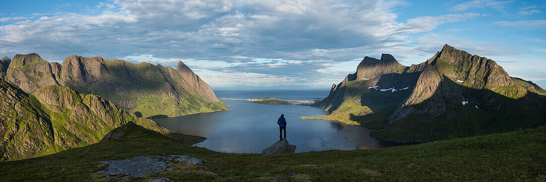 Wanderer mit Panoramablick über den Reinefjord und die umliegenden Berge, in der Nähe von Vindstad, Moskenesøy, Lofoten, Norwegen