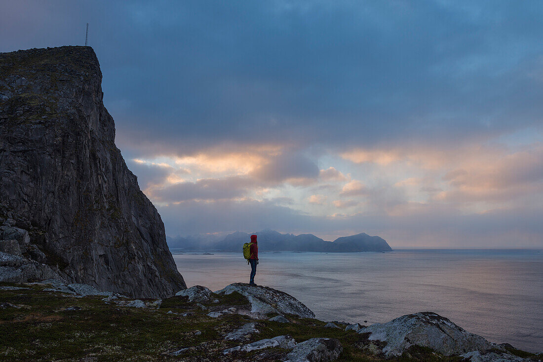 Female hiker stands below MÃ¸ntind, FlakstadÃ¸y, Lofoten Islands, Norway