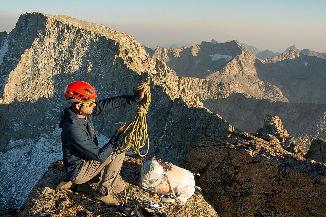 A man coiling a rope on the summit of Mount Mendel along the 8.5 mile Evolution Traverse, John Muir Wilderness, Kings Canyon National Park, Bishop, California.