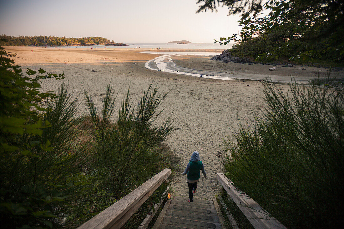 Eine Frau geht zu Mackenzie Beach in der Nähe von Tofino, British Columbia, Kanada.