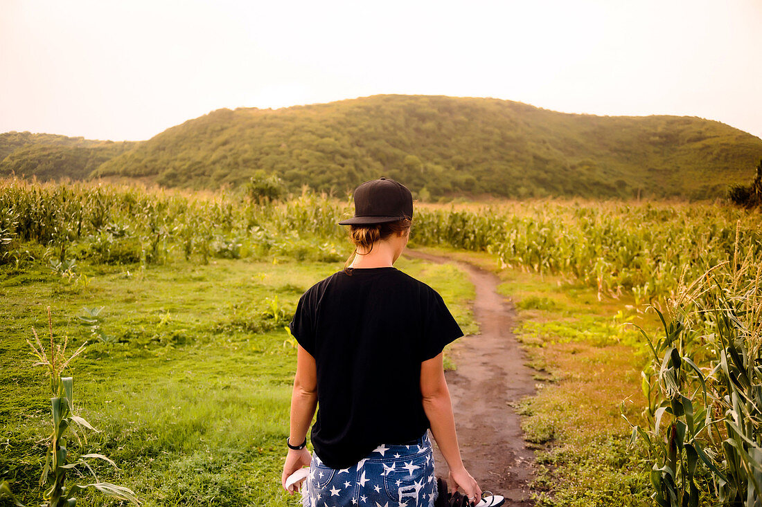 Young woman walking towards corn field