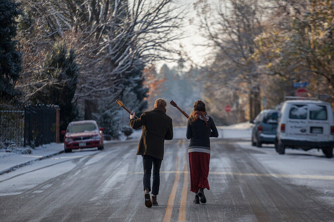 Musicians Ian Van Ornum (left) and Dani Aubert walk down a street in Boulder, Colorado playing their mandolin and banjo.