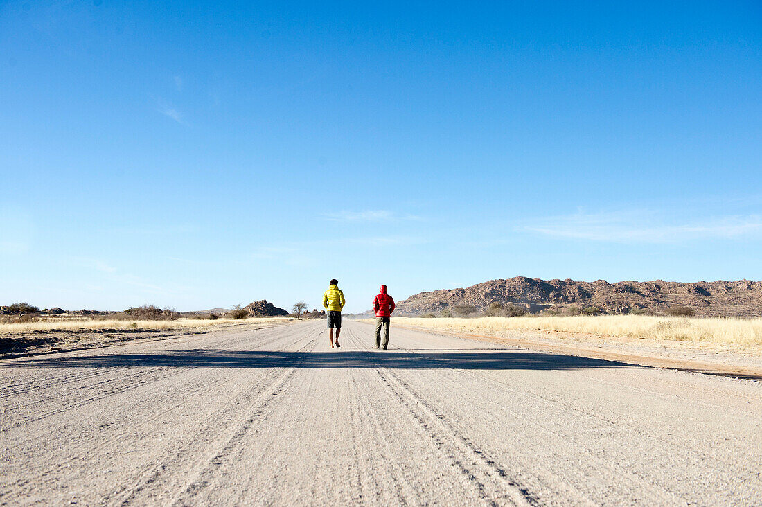 Two man walking on a track in the middel of nowhere , Namibia, Africa.