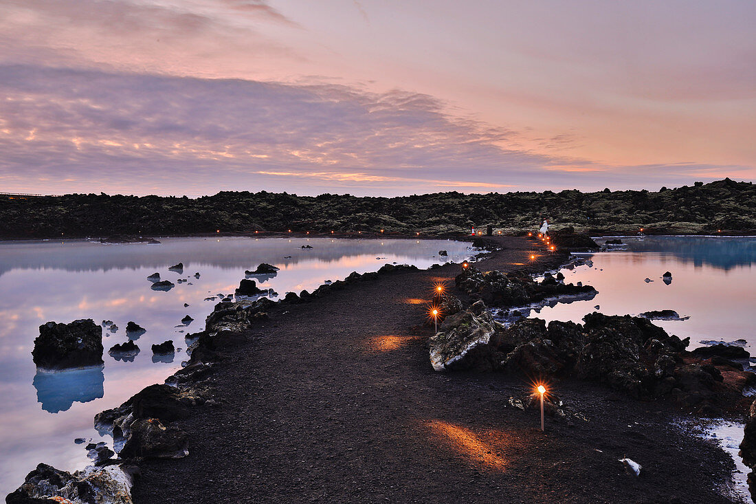 Blue Lagoon pathway among silica water and lava fields at twilight, Reykjanes Peninsula, Iceland.