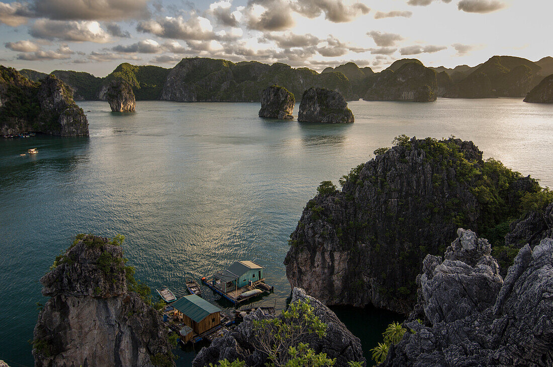A group of floating houses nestles below limestone towers in Halong Bay, Quang Ninh Province