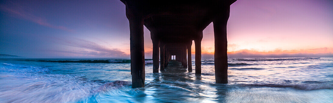 Panoramablick auf den Sonnenuntergang von unterhalb des Manhattan Beach Pier, Los Angeles, Kalifornien, USA