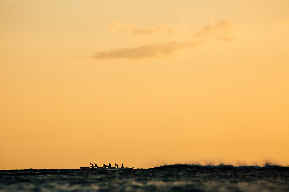 Männer paddeln im Meer bei Sonnenuntergang, Kaimana Beach, Honolulu, Hawaii, USA