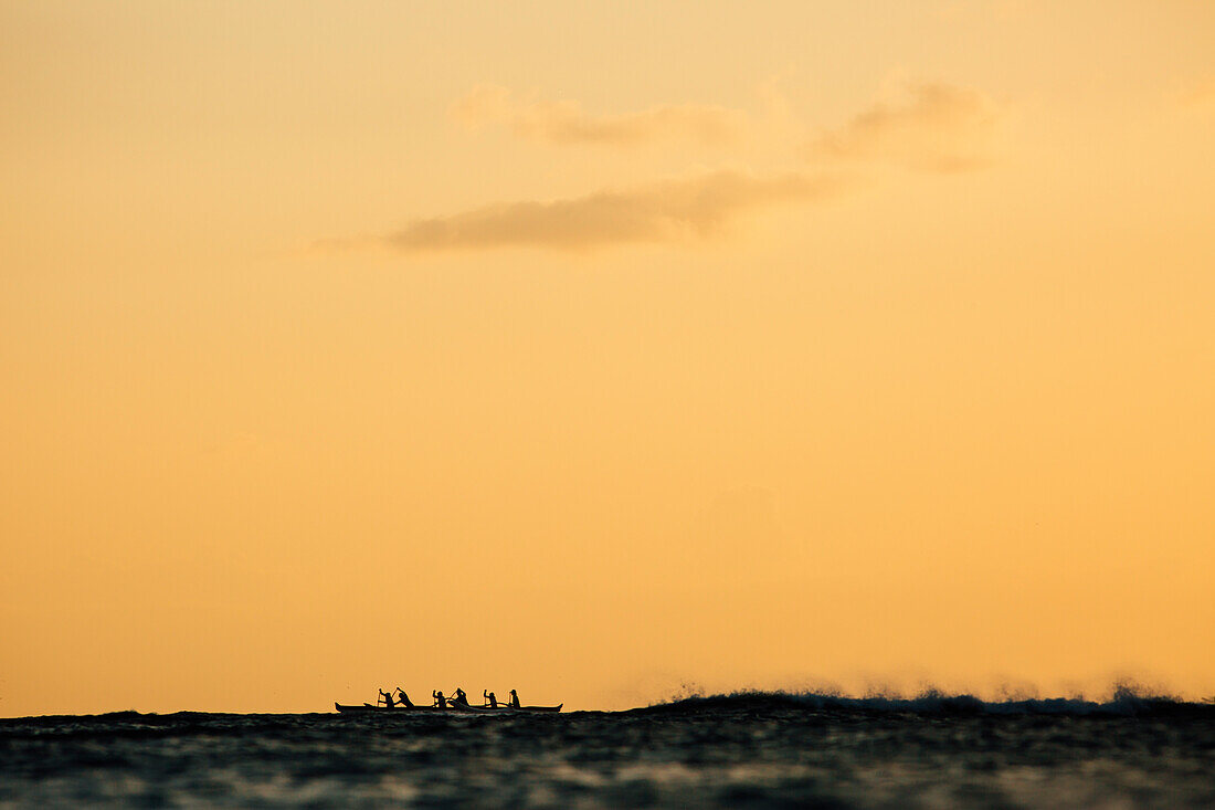 Men paddling in sea at sunset, Kaimana Beach, Honolulu, Hawaii, USA