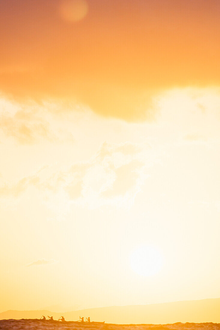 Group of men paddling in sea at sunset, Kaimana Beach, Honolulu, Hawaii, USA