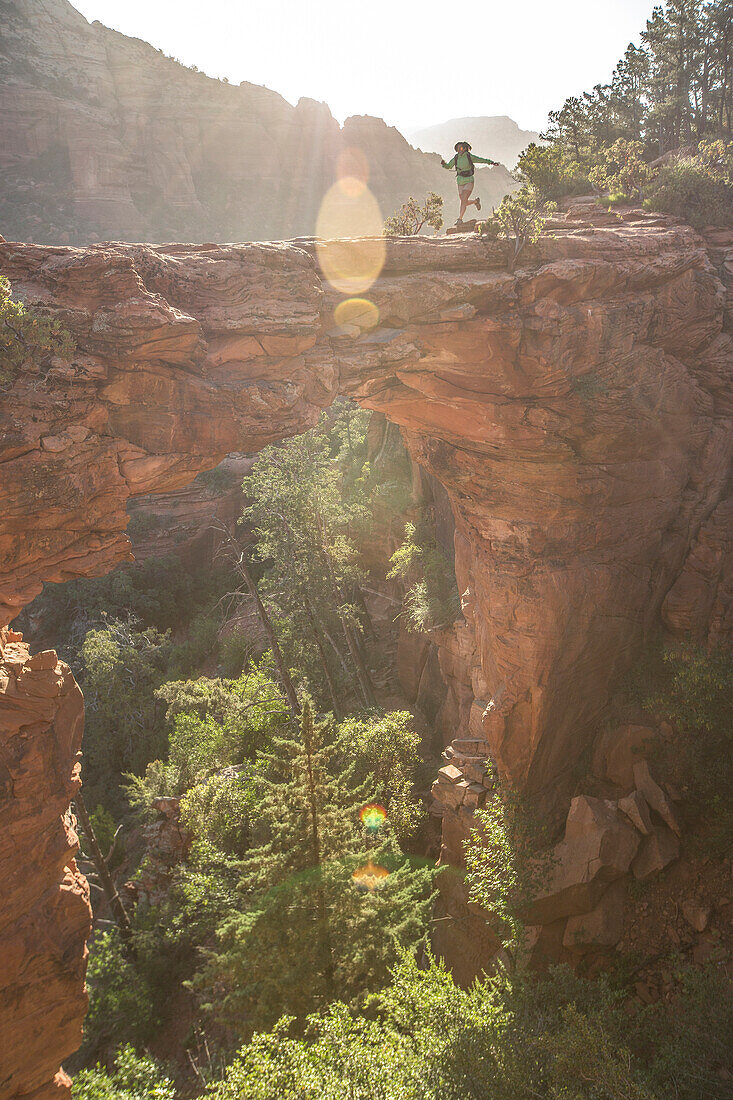 Eine weibliche Wanderer läuft über die Teufelsbrücke in Sedona, Arizona bei Sonnenaufgang.