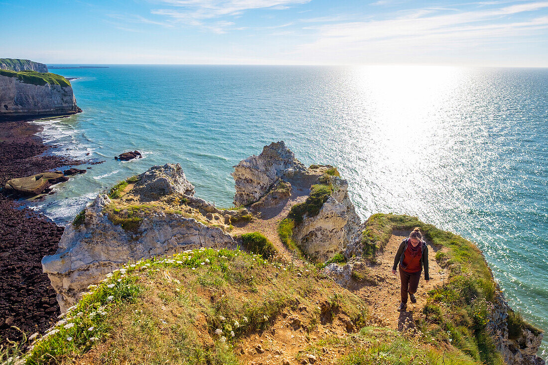 Young woman hiking on cliffs overlooking English Channel, Etretat, Normandy, France
