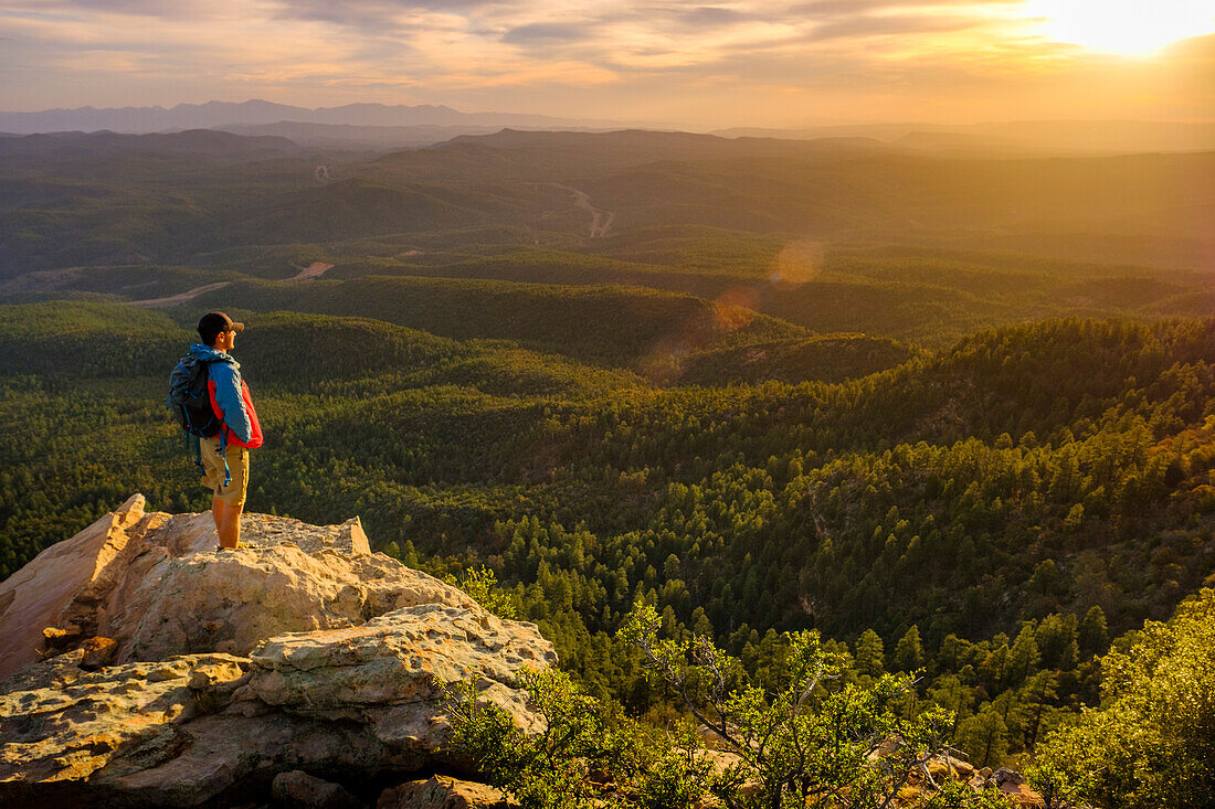 Tranquil scene with backpacker watching sunset from cliff, Mogollon Rim, Arizona, USA