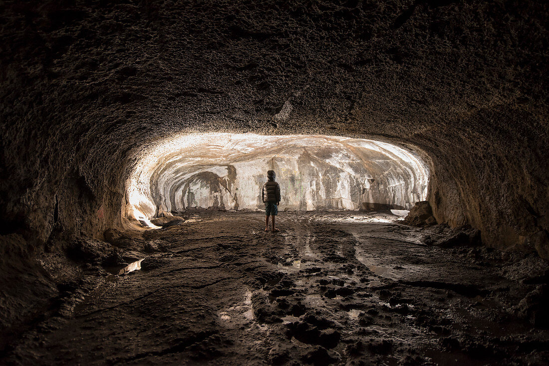 Boy standing alone inside Subway Cave, California, USA