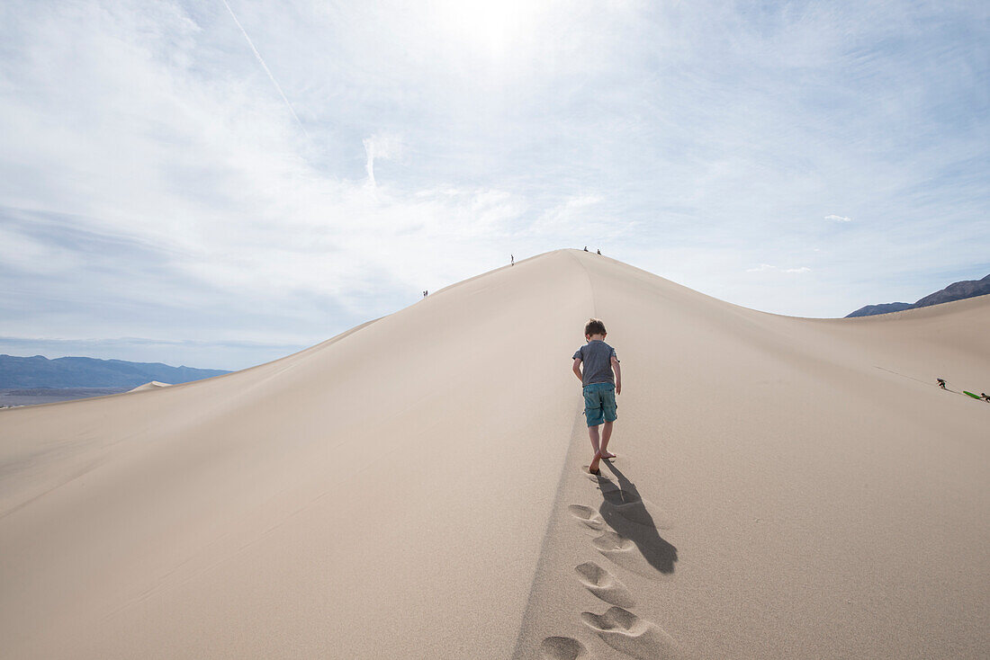 Wolken über junge zu Fuß auf Mesquite flache Sanddünen im Death Valley National Park, Kalifornien, USA