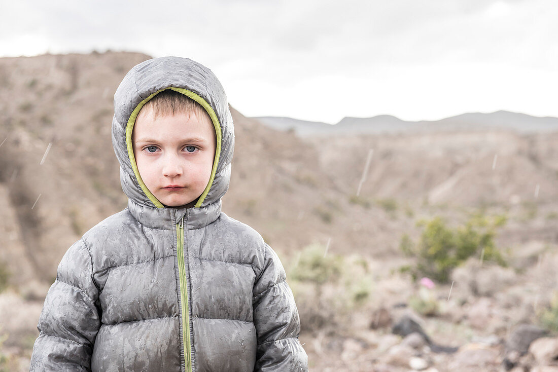 Front view of boy standing in rain shower in Death Valley National Park, California, USA