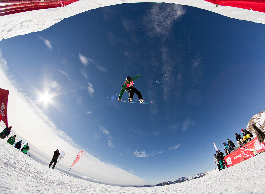 Ein Mann schlägt einen Sprung auf seinem Snowboard während eines Wettbewerbs am Cerro Catedral in Argentinien