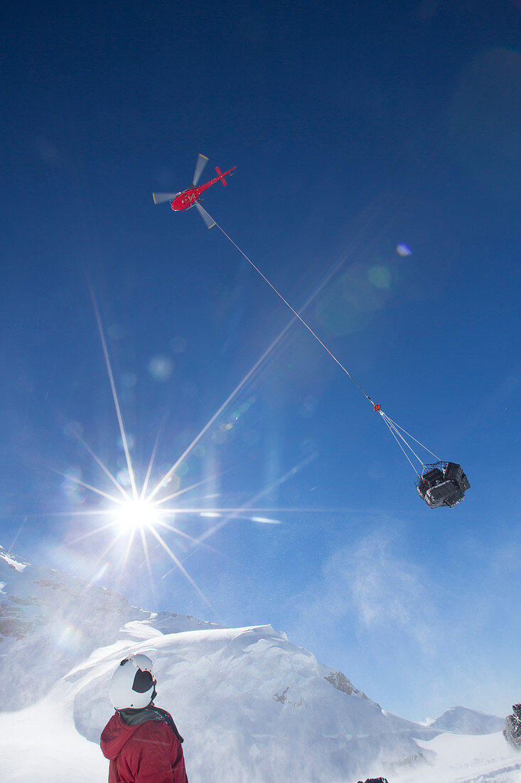 A helicopter is removing waste from a camp on Denali by sling load.