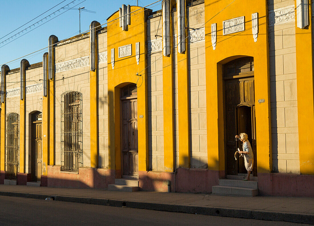 Alte Gebäude entlang der Cienfuegos Straße mit einer alten Dame, die heraus schaut.