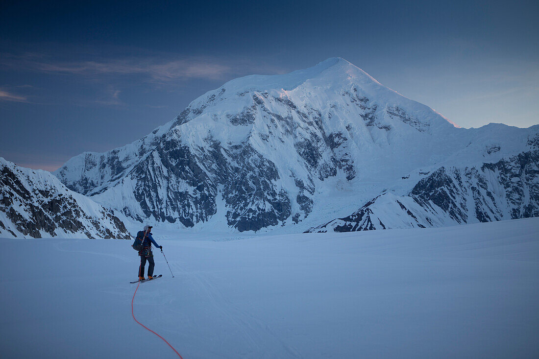 Ein Skibergsteiger auf dem unteren Kahiltna Gletscher des Denali Nationalparks in Alaska, mit Berg Foraker im Hintergrund.