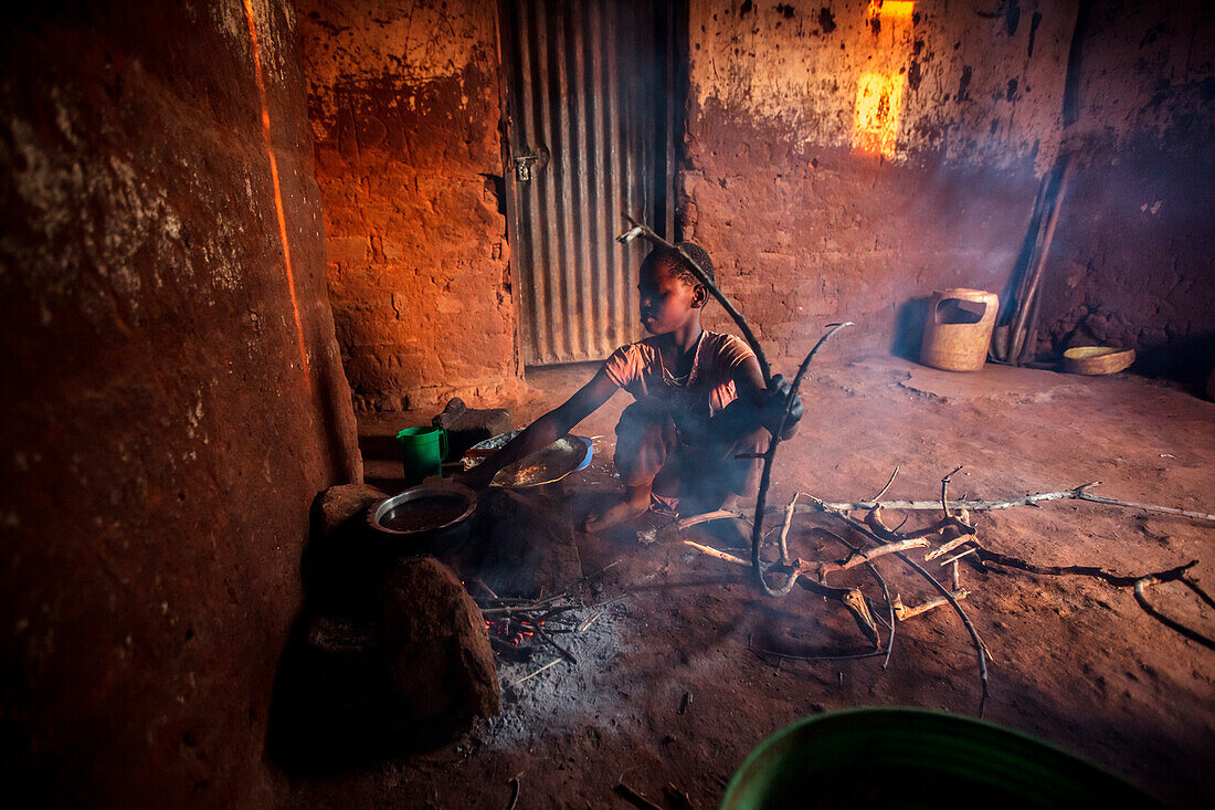 Shadya Jumanne, 11 Jahre Ester Hodaris Schwägerin hilft Ester zu kochen. Sie benutzen einen traditionellen Kochherd. Ester Hodari, 22 Jahre alt, kocht das Abendessen mit dem traditionellen Drei-Steine-Kochherd mit einem Feuer in der Mitte. Diese Kochöfen 