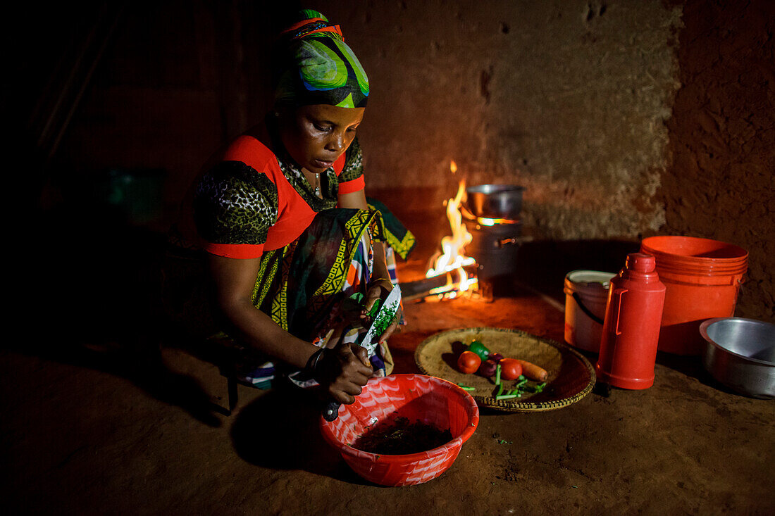 'Mforo, Tansania ein Dorf in der Nähe von Moshi, Tansania. Solar Schwester Unternehmerin Fatma Mziray kochen Abendessen auf ihrem sauberen Kochherd, die Holz verwendet. Fatma Mziray ist eine Solar-Schwester-Unternehmerin, die sowohl saubere Kochherde als 