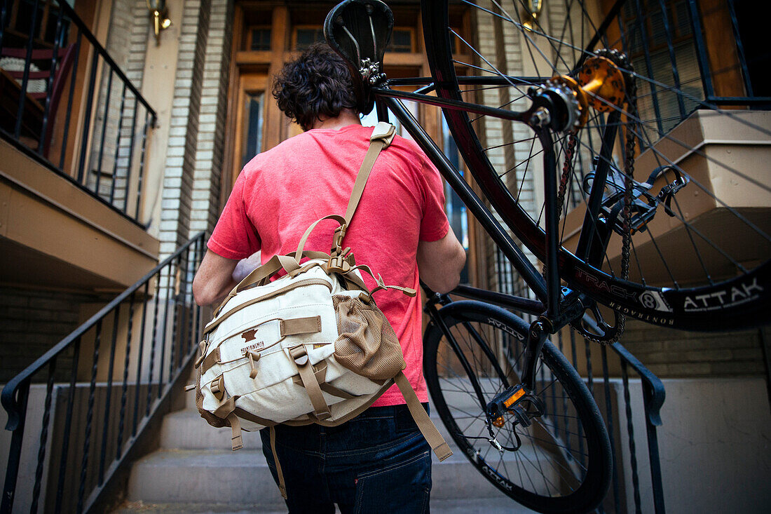 A man carrying his bike up the stairs to his apartment.