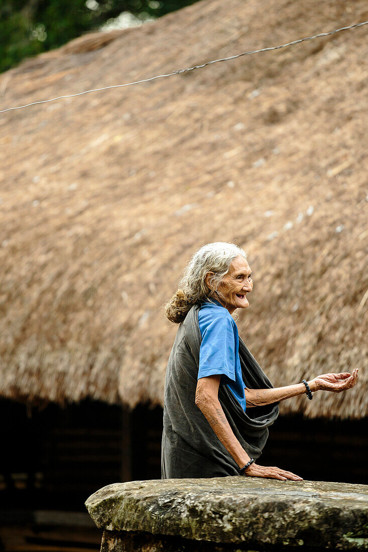 Portrait der lächelnden älteren Frau gegen traditionelles Haus, Sumba, Indonesien