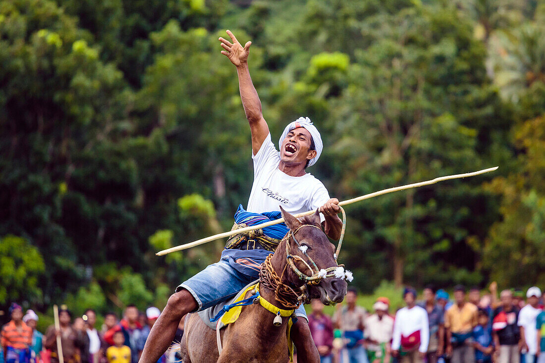 Man hebt Hand und Reitpferd mit Speer auf Pasola Festival, Insel Sumba, Indonesien