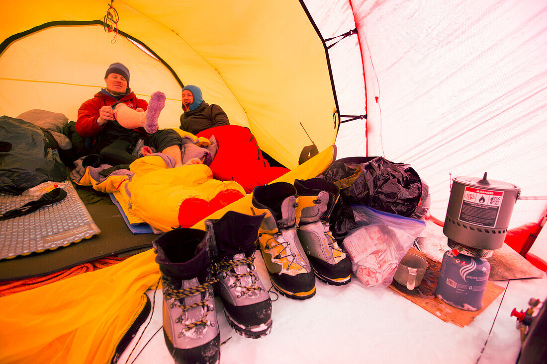 Zwei Bergsteiger liegen in einem Zelt im High Camp auf Denali in Alaska. Am frühen Morgen machen sie einen Gipfeltransfer zum höchsten Berg Nordamerikas.