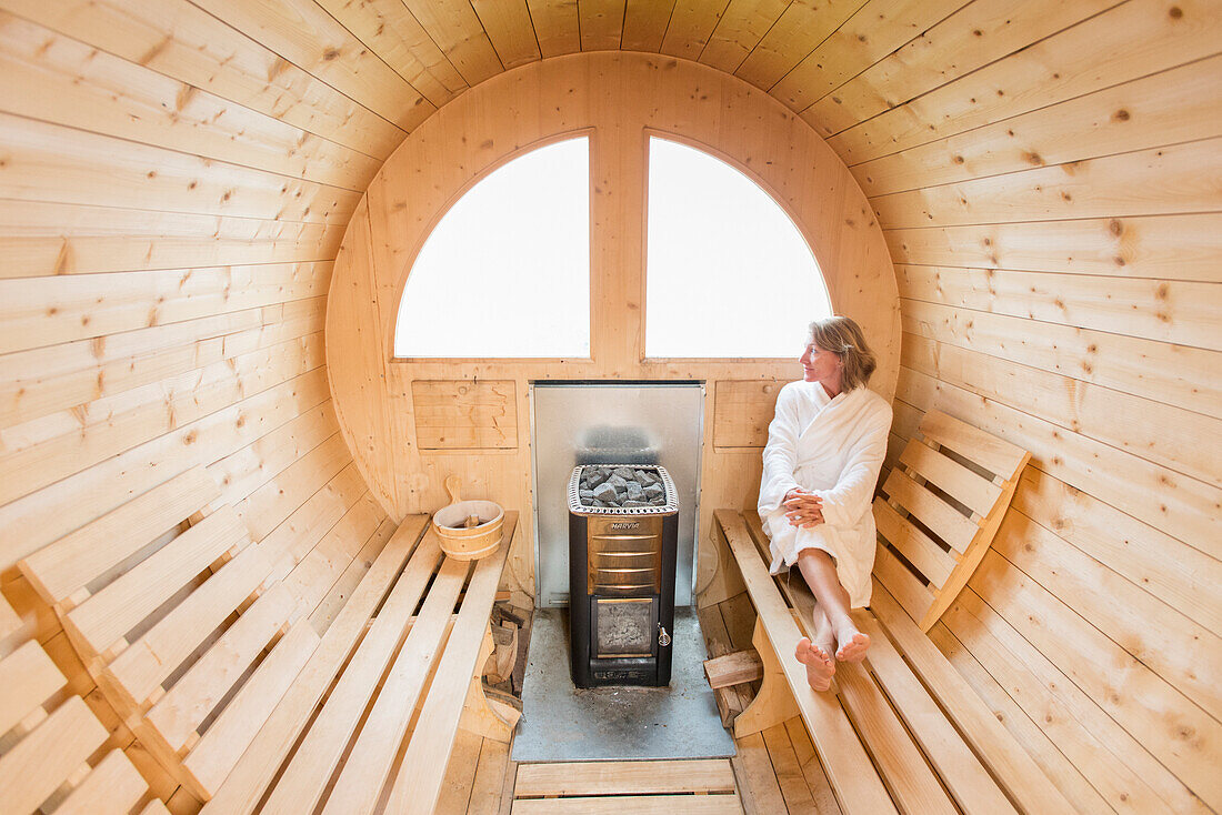 Eine Frau, die in der hölzernen Sauna von Rifugio Lagazuoi in den Dolomit, Italien sich entspannt