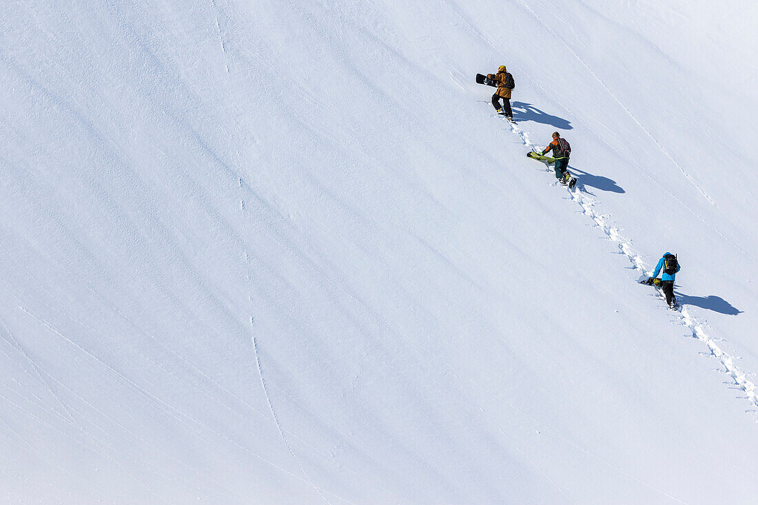 Snowboarders Hike Up In A Group To A Clean Canvas Of Snow On The Way To Their Lines