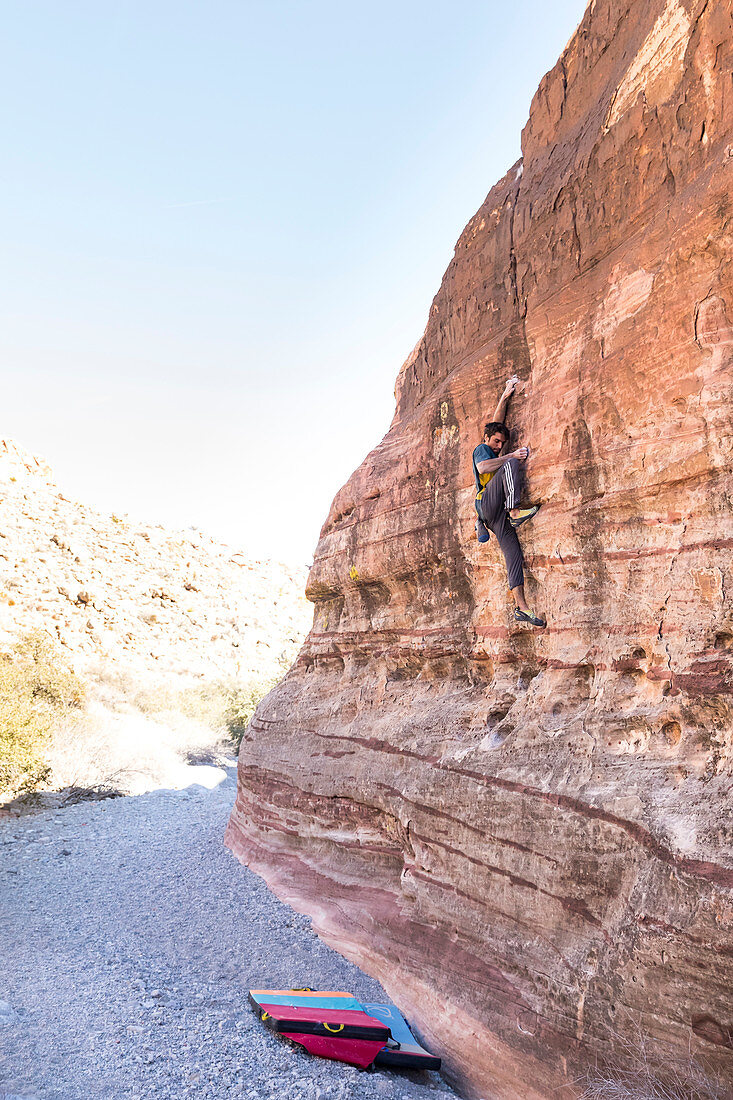 A man climbs on a tall wall alone in red rocks national park, Nevada