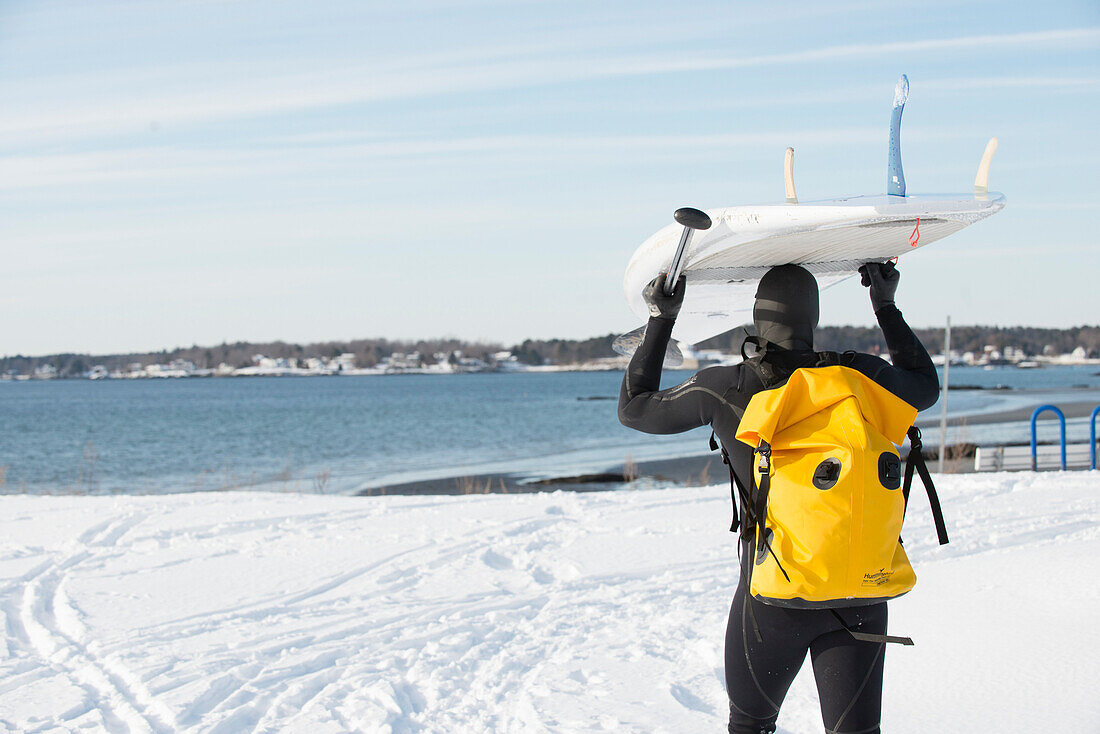 Paddleboarder Überschrift in den kalten Atlantik an einem sonnigen Tag