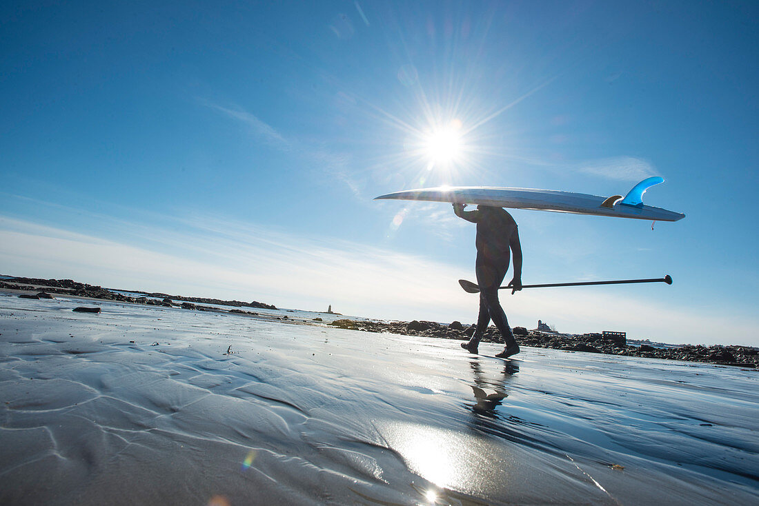 Paddleboarder Überschrift in den kalten Atlantik an einem sonnigen Tag