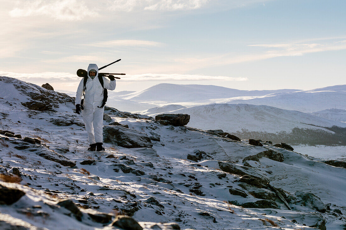 Ein Fotograf mit einem Stativ über den Rücken zu Fuß auf verschneiten Landschaft