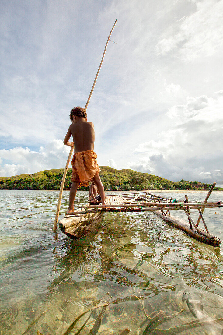 Children playing with a outrigger canoe in the village of Hessessai Bay at PanaTinai (Panatinane)island in the Louisiade Archipelago in Milne Bay Province, Papua New Guinea.  The island has an area of 78 km2. The Louisiade Archipelago is a string of ten l