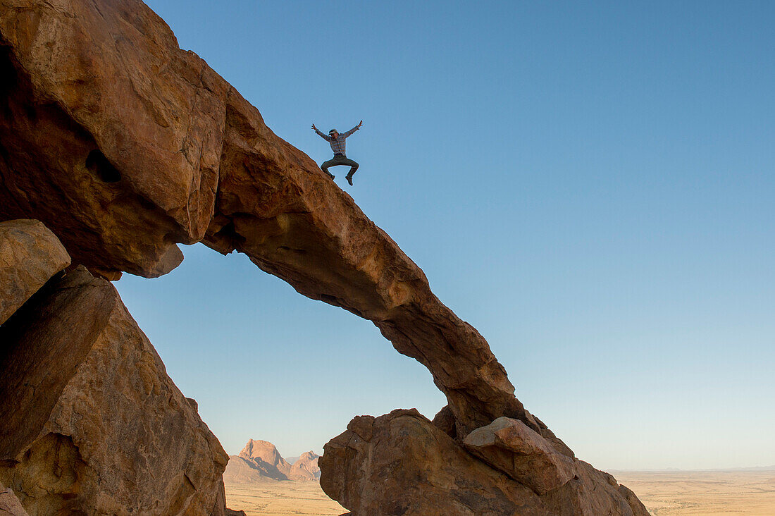 Foto des Menschen springen auf Felsbogen, Spitzkoppe, Erongo Region, Namibia