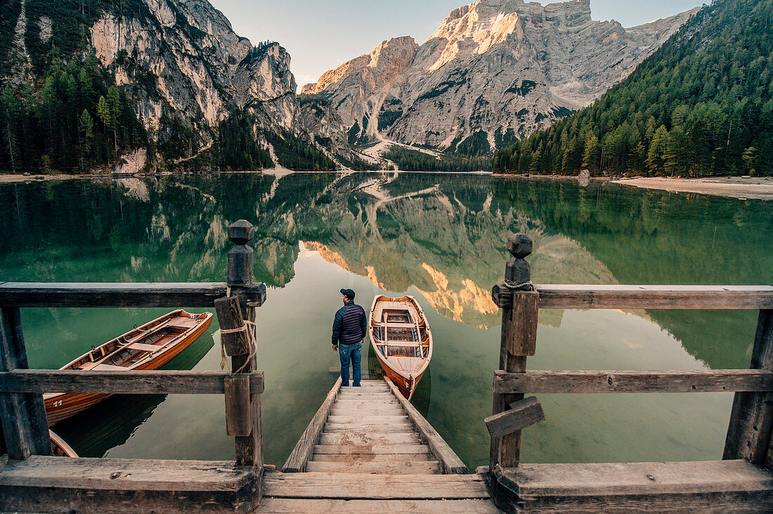 man standing at a boathouse at Lago di Braies, dolomites, south tyrol, trentino, italy, europe