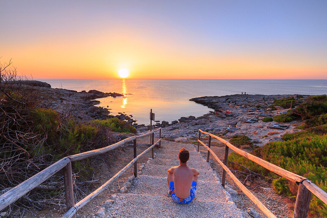 Tourist watches the sunset at Cala Tramontana, Tremiti Islands, Foggia, Puglia, Italy