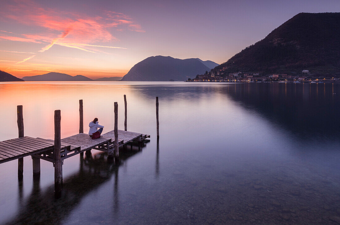 A girl on the pier of Sulzano during a winter sunset, Brescia Province, Iseo Lake, Lombardy, Italy