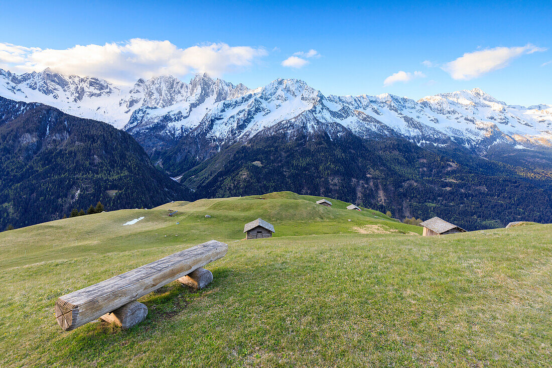 Wiesen und Holzhütten umrahmt von schneebedeckten Gipfeln im Morgengrauen Tombal Soglio Bregaglia Valley Kanton Graubünden Schweiz Europa