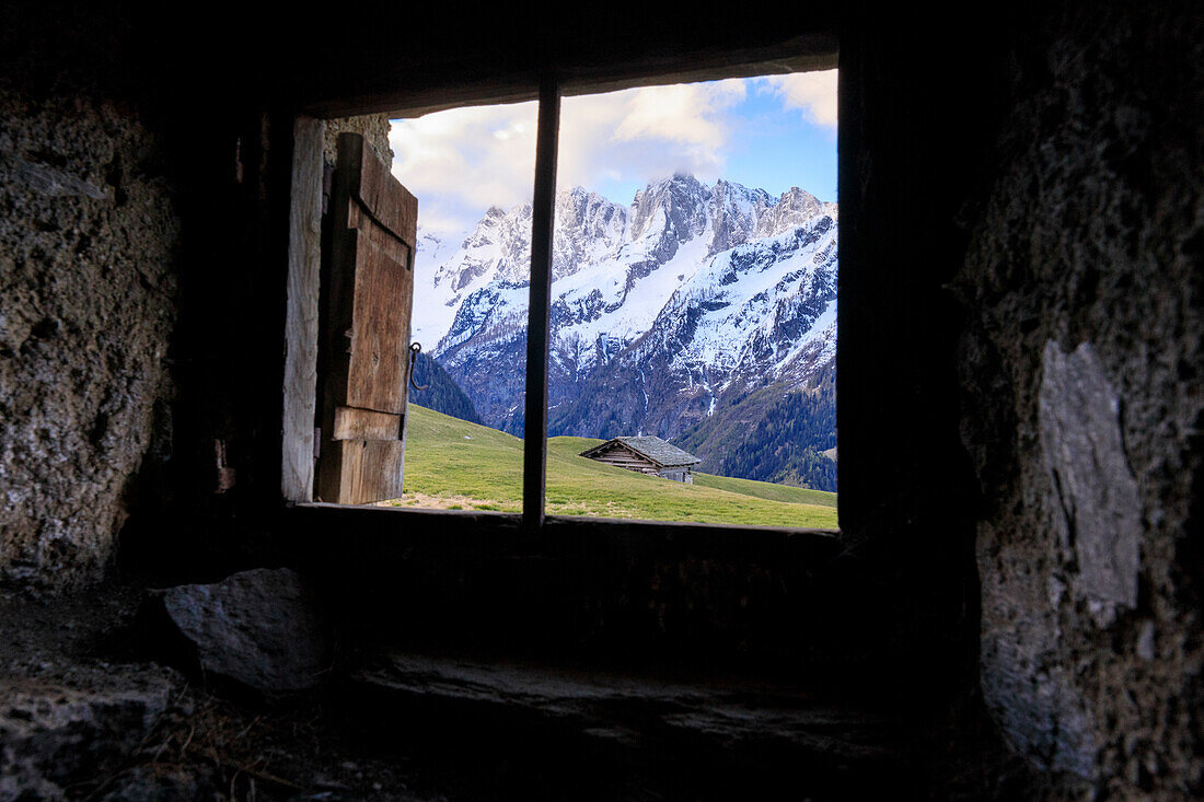 Blick auf grüne Wiesen in der Dämmerung von der verlassenen entsteinten Hütte Tombal Soglio Bregaglia Valley Kanton Graubünden Schweiz Europa