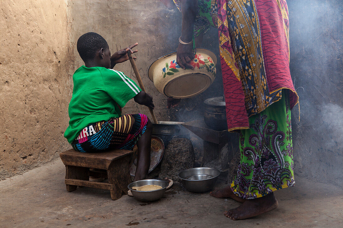 A young girl helping her mother cook at their home in Tinguri, Ghana, West Africa, Africa