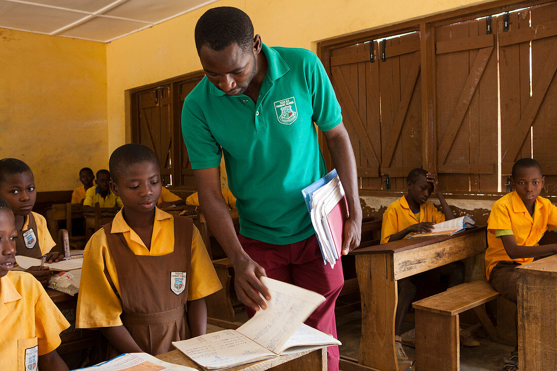 Ein männlicher Lehrer unterrichtet ein Klassenzimmer von Kindern an einer Grundschule in Ghana, Westafrika, Afrika