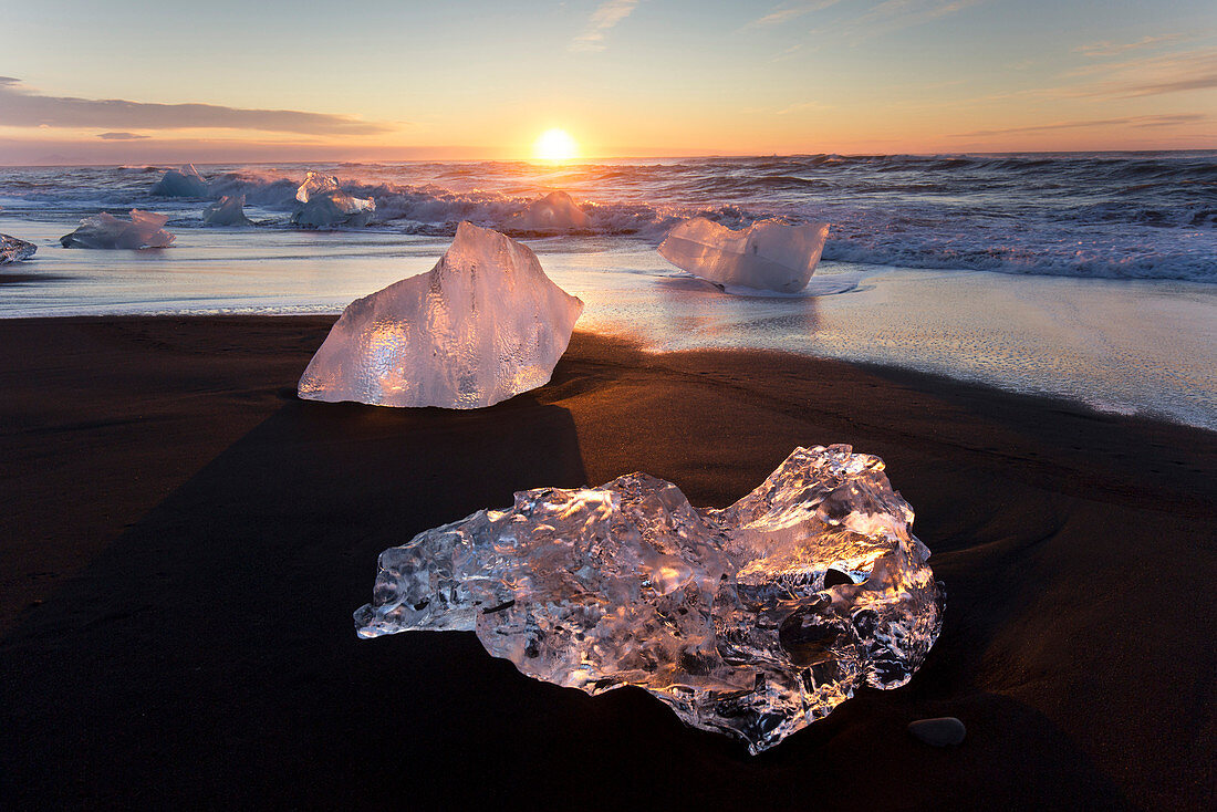 Gläserne Stücke von Eis auf vulkanischen schwarzen Sandstrand bei Sonnenaufgang, in der Nähe von Jokulsarlon Lagune, Südisland, Polargebiete