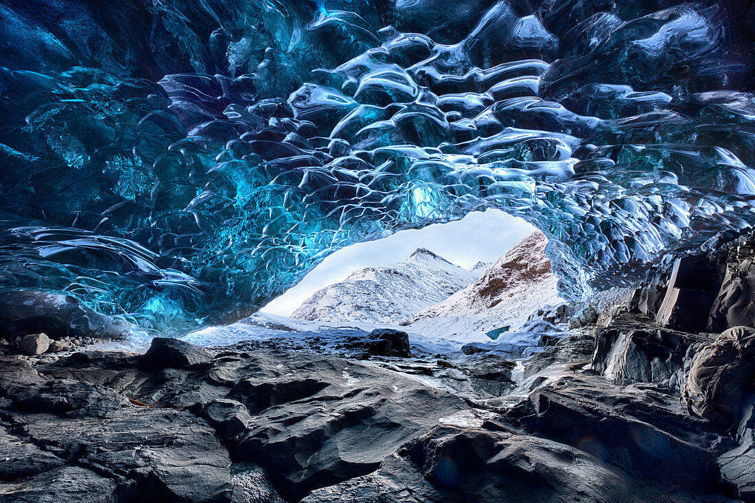 Blick von innen Eishöhle unter dem Vatnajokull-Gletscher in Richtung schneebedeckte Berge, in der Nähe von Jokulsarlon Lagune, Südisland, Polargebiete